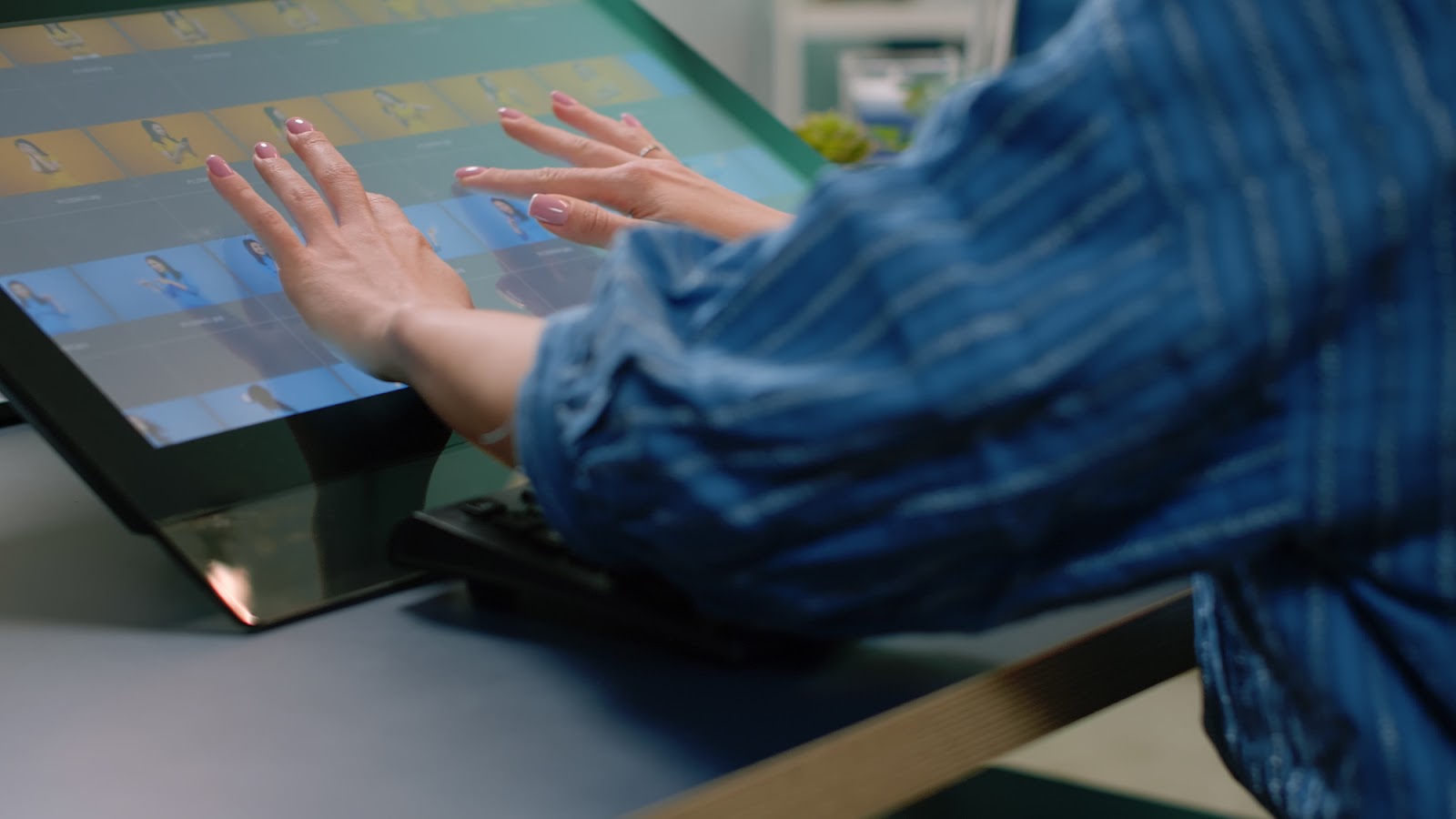 Des mains manipulent une interface sur un grand écran tactile horizontal