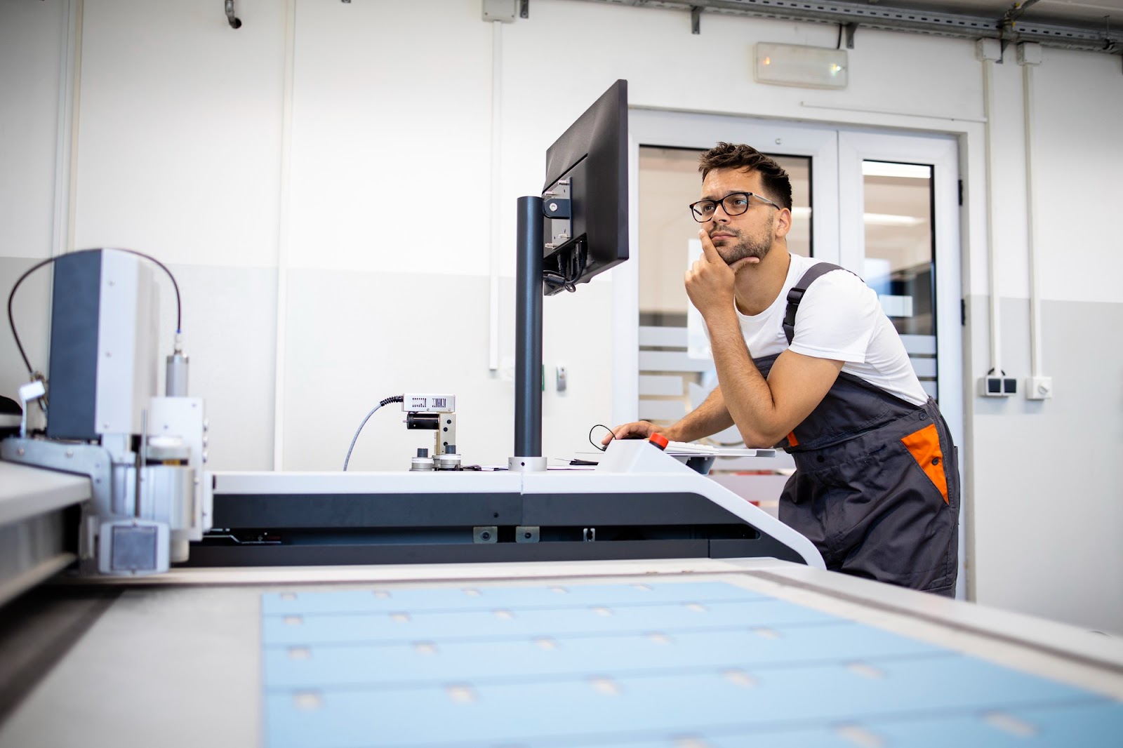 Opérateur pensif devant l’écran de contrôle d’une machine de découpe industrielle